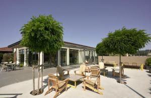 een patio met tafels, stoelen en bomen bij Langre Homely Rooms in Galizano