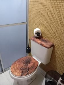 een badkamer met een toilet en een houten stoel bij UniversiFlat in Ponta Grossa