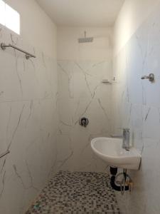 a white bathroom with a sink and marble walls at Casa alexander in Acapulco