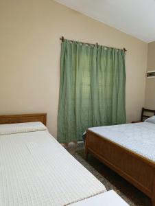 - une chambre avec 2 lits et un rideau vert dans l'établissement Casa en centro de Icho Cruz, à Villa Icho Cruz