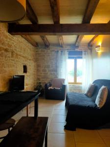 a living room with a blue couch and a tv at L'écurie du Mas in Lamothe-Cassel
