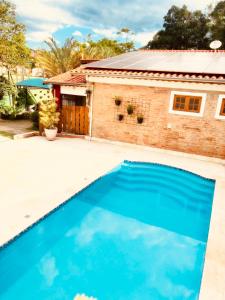 a blue swimming pool in front of a house at Villa Cottage Pousada in Monte Alegre do Sul