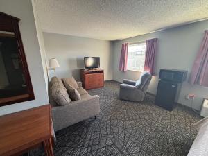un soggiorno con divano, sedia e TV di Covered Bridge Inn a Winterset