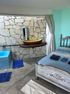 una camera da letto con un letto e un muro di pietra di Chalé Vista Mar a Ilhabela