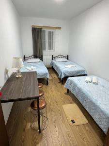 Cette chambre comprend 3 lits, une table et des chaises. dans l'établissement NAPO HOTEL სასტუმრო ნაპო, à Zugdidi