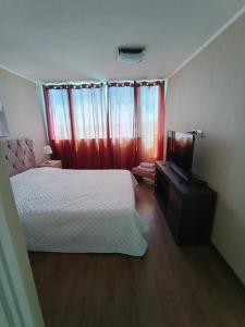 een slaapkamer met een bed en een televisie en gordijnen bij Edificio Concepto in Calama +4 foto's