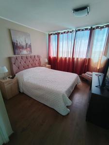 een slaapkamer met een wit bed en rode gordijnen bij Edificio Concepto in Calama