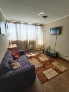 een woonkamer met een blauwe bank en een groot raam bij Edificio Concepto in Calama