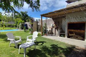 twee witte stoelen en een grill in een tuin bij Arrabal.Tupungato in Tupungato