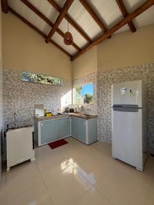 a kitchen with blue cabinets and a white refrigerator at Vila Floresta - Arraial D'Ajuda in Porto Seguro