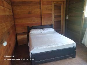 a small bed in a room with wooden walls at Chema in Mocoa +8 photos