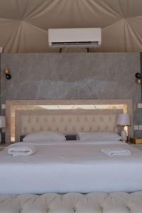 een slaapkamer met een groot wit bed in een tent bij Rum Plaza Luxury Camp in Wadi Rum
