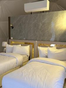 2 bedden in een kamer met witte lakens en kussens bij Rum Plaza Luxury Camp in Wadi Rum