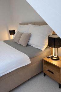 - un lit avec des draps et des oreillers blancs à côté d'une table dans l'établissement Apartmánový dom Adriana, à Zuberec