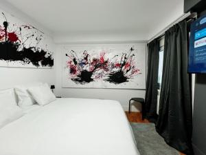 a bedroom with a white bed and paintings on the wall at Suite en Sol 2 P in Madrid +13 photos