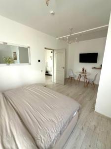 een witte slaapkamer met een bed en een tafel bij Cleo Residence 2 Ghiroda in Ghiroda +11 foto's