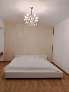 een witte slaapkamer met een bed en een kroonluchter bij 18 Piata Sfatului in Braşov