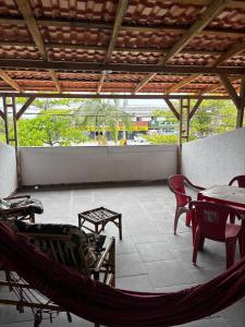 een veranda met een hangmat en een tafel en stoelen bij Pousada Ju&Ju à 400 mts DA PRAIA in Pontal do Paraná