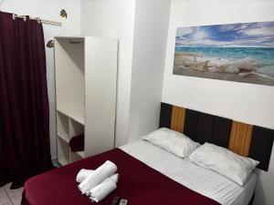 een slaapkamer met een bed met handdoeken erop bij Pousada Ju&Ju à 400 mts DA PRAIA in Pontal do Paraná