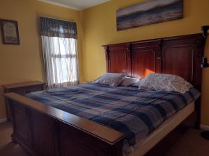 une chambre avec un lit avec une tête de lit en bois et une fenêtre dans l'établissement Ventnor Island Beach House, à Ventnor City