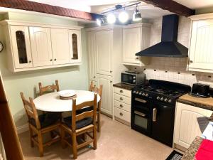 a kitchen with a table and a stove top oven at Village Cottage Marple in Marple