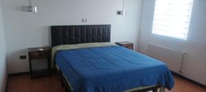 a bedroom with a bed with a blue blanket at Pequeño Depa 2 personas in Puerto Montt