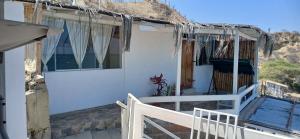 een wit huis met een balkon en een heuvel op de achtergrond bij Casa de playa in Tumbes