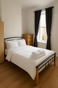 ein Schlafzimmer mit einem großen weißen Bett mit einem Fenster in der Unterkunft Spacious double room close to Wimbledon Park station, 20 min to central in London