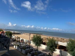 einen Strand mit Tischen und Stühlen und das Meer in der Unterkunft Villa Ô Dunes in Châtelaillon-Plage