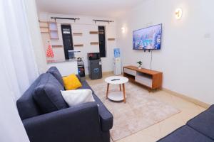 a living room with a blue couch and a table at Modern 1BR Apartment in Membley & near Ruiru Bypass, Kenyatta University & AMREF, Fast WiFi & Parking-Ruiru Membley in Ruiru +4 photos