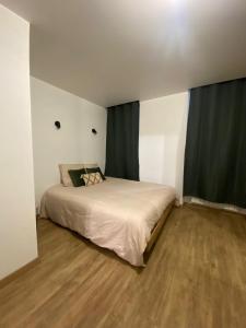 een slaapkamer met een groot bed en groene gordijnen bij L'oranger in Lons-le-Saunier