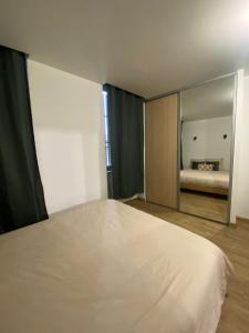 een slaapkamer met een groot wit bed en een spiegel bij L'oranger in Lons-le-Saunier