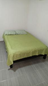 a bed with a green blanket on top of it at Casa alexander in Acapulco