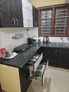 a kitchen with a black counter top with a sink at Rove Haven Condo in Bangalore