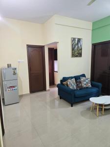 a living room with a blue couch and a refrigerator at Rove Haven Condo in Bangalore