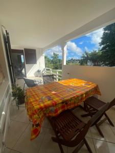 a table and chairs on a balcony with a tablecloth at Rayon des îles bien désirée in Saint-François
