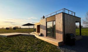 a small wooden house with an umbrella in a field at Airpark-Lodge in Lärz