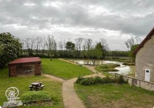 ein Garten mit Picknicktisch und Teich in der Unterkunft Chambre d hôtes prêt du parc du pal in Chevagnes