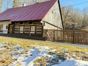 a wooden building with a red roof and a fence at Chalupa pod jelení skálou in Dolni Dvur