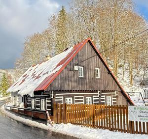 a house with a red roof in the snow at Chalupa pod jelení skálou in Dolni Dvur