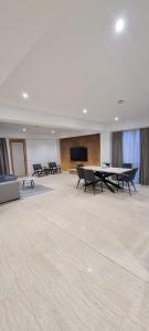 Großes Zimmer mit Tischen und einem Flachbild-TV. in der Unterkunft Eroilor Apartments in Curtea de Argeş