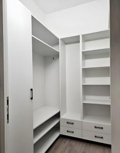 un dressing blanc avec des étagères blanches dans l'établissement Luxury District - Panoramic View Urban Apartment, à Târgu-Mureş