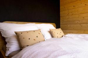 a bed with white sheets and pillows at Woodydrem in Hruštín