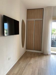 a living room with a tv and a wooden cabinet at Aires del Rio Apart in Villa de Soto