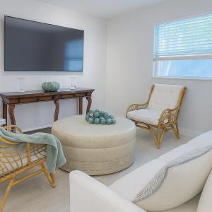 a living room with a flat screen tv and chairs at Tropical Pool Haven Minutes to Downtown & beaches in Naples