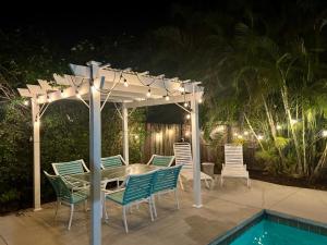 a table and chairs under a pergola next to a pool at Tropical Pool Haven Minutes to Downtown & beaches in Naples