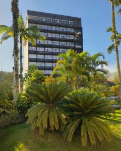a large building with palm trees in front of it at Hotel Franco Blumenau in Blumenau
