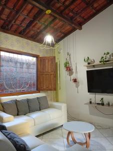 a living room with a white couch and a tv at Casa Beija Flor in Itacaré