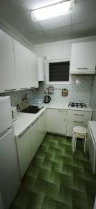 a kitchen with white cabinets and a green floor at Playa de Sant Adrià de Besòs in Sant Adria de Besos