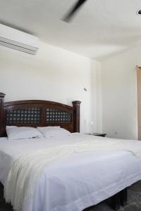 a bedroom with a large bed with white sheets at Casa Calandria in Chicxulub